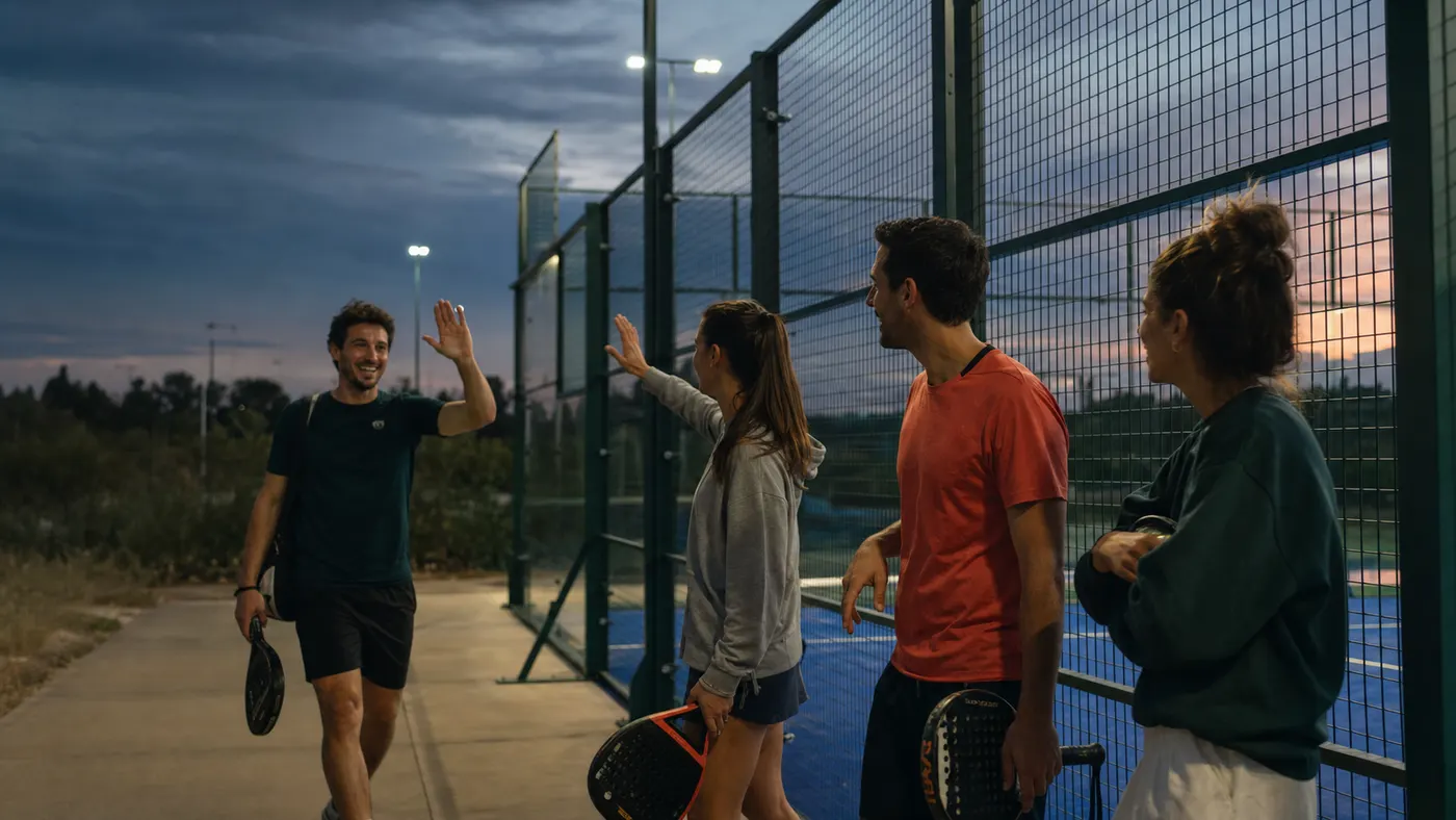 Padel group greeting the person arriving to complete the match